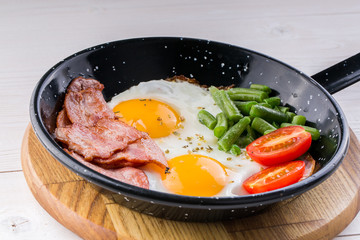 Fried egg on a pan served with tomato and asparagus