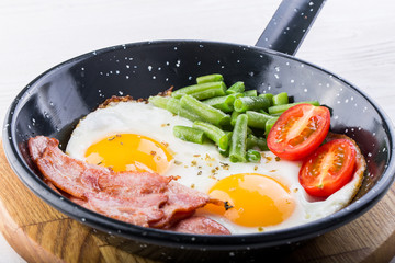 Fried egg on a pan served with tomato and asparagus