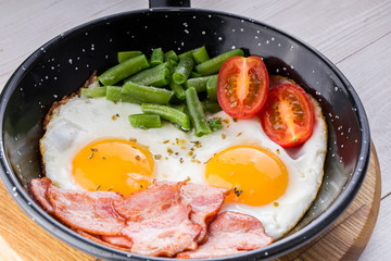 Fried egg on a pan served with tomato and asparagus
