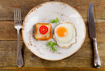 Breakfast with fried egg, toast and fresh vegetables.