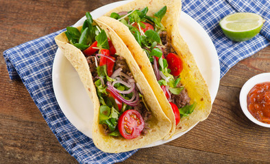 Two tacos on  a wooden table.