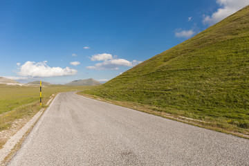 Strada di montagna tra verdi pendii e cielo blu