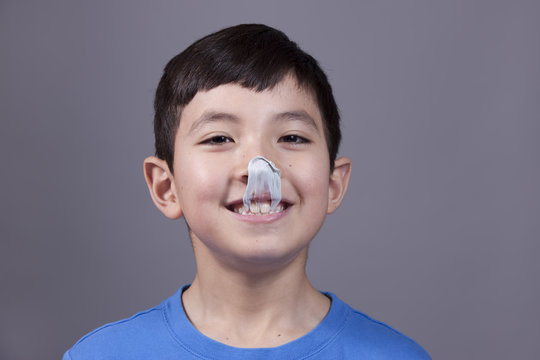 Boy smiles at gum on his nose.