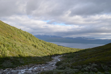River through willow shrubs, mountains and lake Torneträsk, Abisko, subarctic Swedish Lapland