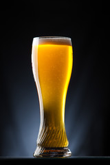 Tall glass of beer over a dark background