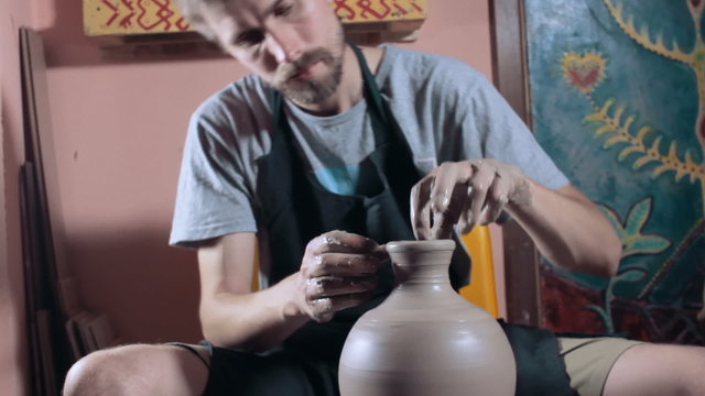 Pottery sculpting a traditional clay pot, wide angle, dolly shot
