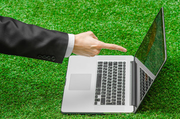 Work outdoors and businessman topic: human hands show the gestures in a black suit and an open notebook on a background of green grass