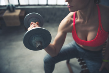 Fototapeta na wymiar Closeup on fitness woman lifting dumbbell in loft gym