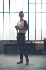 Fitness woman with bottle of water in loft gym