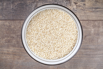 Sesame seeds in bowl on wooden background