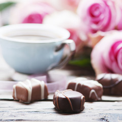 Pink roses, coffe and chocolate on the wooden table