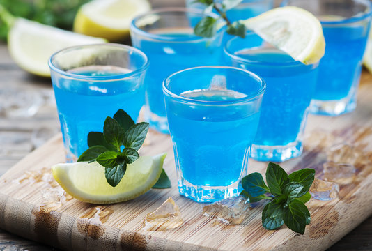 Blue curacao liqueur with lemon on the wooden table