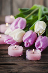 Fototapeta na wymiar Pink and white tulips and candles on the wooden table