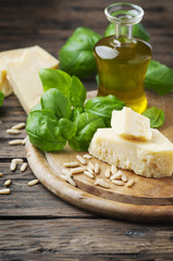 Basil, cheese, pine and olive oil on the wooden table
