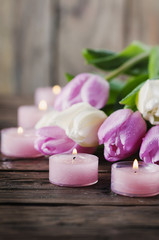 Fototapeta na wymiar Pink and white tulips and candles on the wooden table