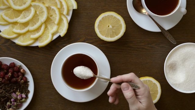 Putting sugar into a cup of tea