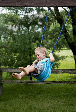 Boy Playing On A Backyard Tire Swing