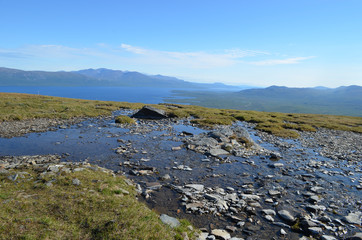 Fototapeta na wymiar Rocks in a wide shallow stream in subarctic mountains, Swedish Lapland
