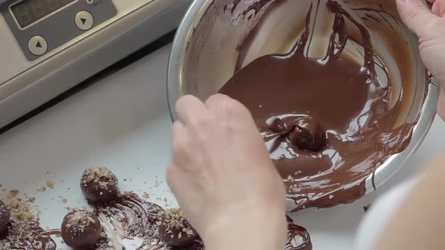 Over shoulder of baker making chocolate mousse truffles by hand
