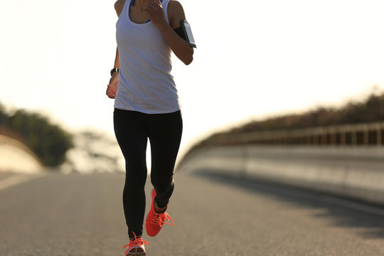 young fitness woman runner running on sunrise road