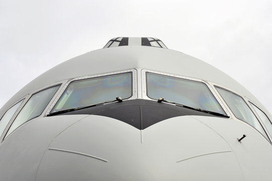 Front view close-up of a transportation airplane with cloudy sky
