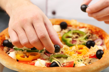Cook making delicious pizza at the restaurant, close-up