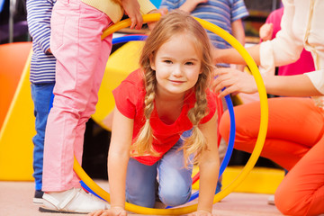 Girl play a game in kindergarten crawl though hoop