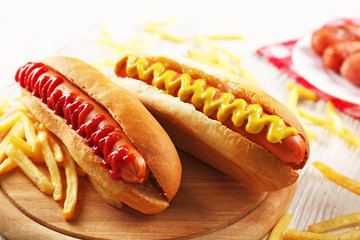Hot dogs and fried potatoes on wooden cutting board closeup