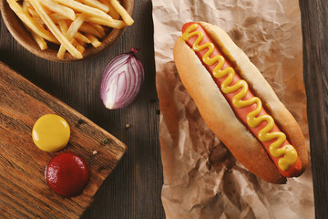 Hot dog with fried potatoes on craft paper closeup