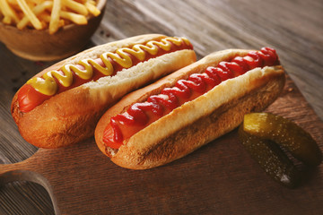 Hot dogs with fried potatoes on cutting board