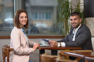 Young businesswoman and businessman analyzing paperwork in a coffee shop