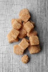 Pile of brown sugar cubes on wooden background
