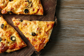 Delicious sliced pizza on wooden board, close up