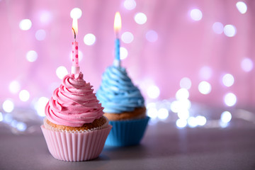 Two cupcakes with candle on a glitter background