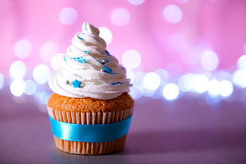 Cupcake with white cream icing on a glitter background, close up