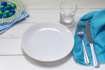 table setting with blue and turquoise easter eggs, white plate,