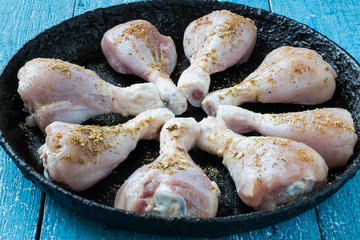 Raw chicken drumsticks in a cast iron pan