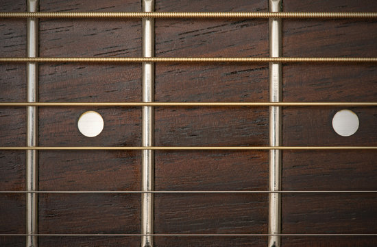 close-up macro of guitar strings and fret board
