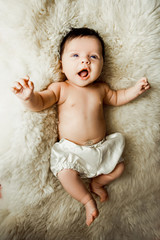 Newborn baby lying on white blanket and smiling