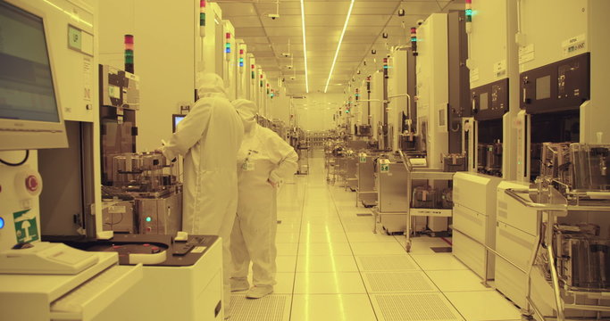 Workers in clean suits on the production floor of a semiconductor fabrication facility
