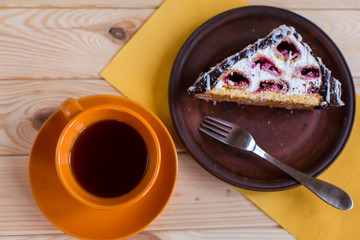 cup of tea and cake with cherries on a wood background
