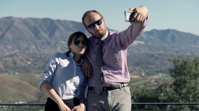 Young business couple taking selfie photo with cellphone on terrace in the country
