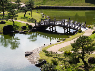 Obraz premium Traditional Japanese garden with pond and wooden arched bridge