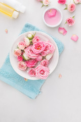 Spa settings with roses. Fresh roses and rose petals in a bowl of water and various items used in spa treatments
