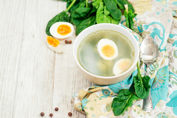 
healthy lunch , green soup with sorrel or spinach , boiled egg and spices on wooden background