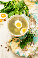 
healthy lunch , green soup with sorrel or spinach , boiled egg and spices on wooden background