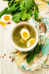 
healthy lunch , green soup with sorrel or spinach , boiled egg and spices on wooden background