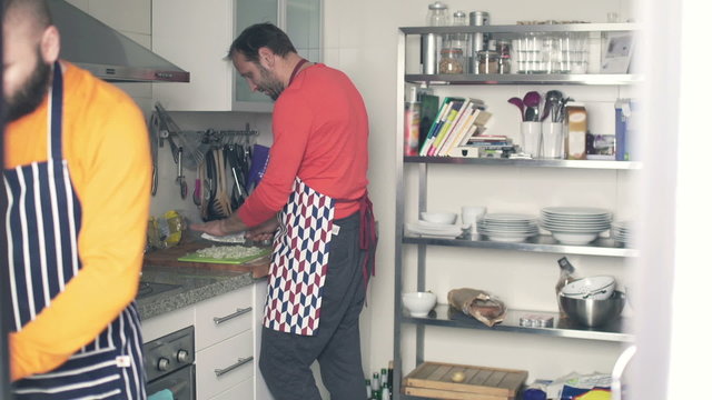 Two men in aprons cooking in the kitchen at home
