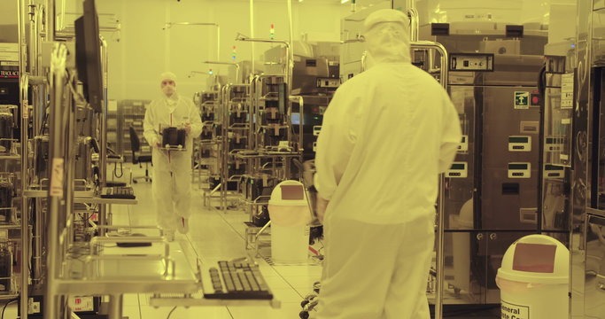 Workers in clean suits on the production floor of a semiconductor fabrication facility