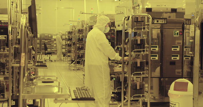 Workers in clean suits on the production floor of a semiconductor fabrication facility